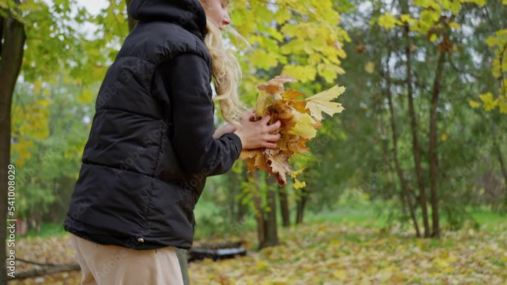Slow motion young beautiful happy woman stands in park and smells leaves of tree Slow motion young beautiful happy woman stands in park and smells leaves of tree