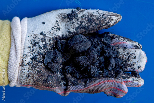 Worker holding oil sands, Suncor Facility, north of Fort McMurray, Alberta, Canada. photo
