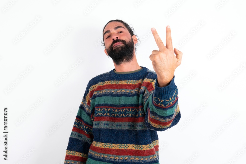 Naklejka premium Caucasian man with beard wearing sweater over white background smiling and looking friendly, showing number two or second with hand forward, counting down
