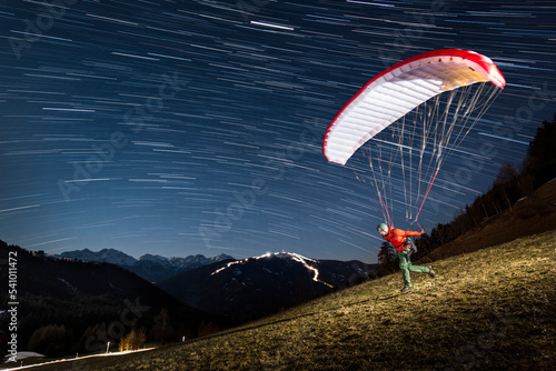 Man taking off while speed flying in Alps at night, Brunico, South Tyrol, Italy photo