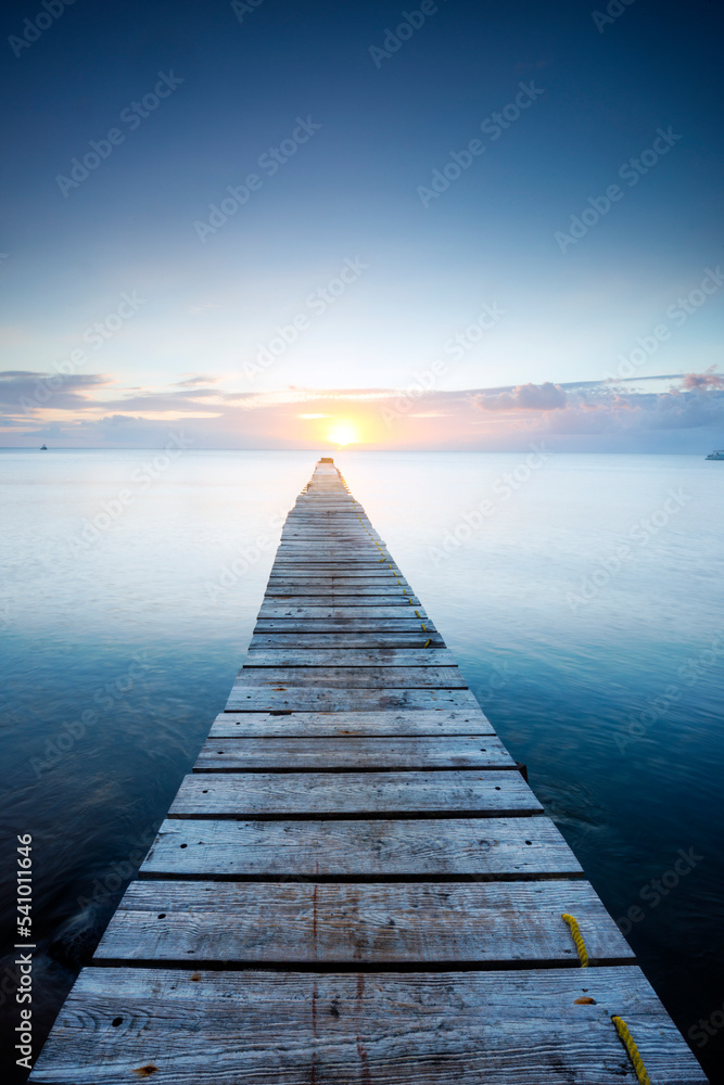 A beautiful sunset over the Caribbean Sea on a pier at the Portsmouth Beach Hotel in the town of Portsmouth on the island of Dominica. A beautiful sunset over the Caribbean Sea on a pier at the Portsmouth Beach Hotel in the town of Portsmouth on the island of Dominica.
