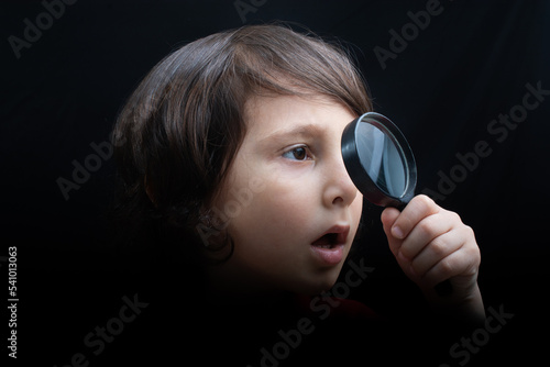 Portrat of a young boy looking through the magnifying glass