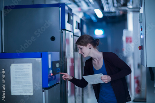 Young female engineer using a digital tablet and controlling a switchgear in control room, Freiburg im Breisgau, Baden-Württemberg, Germany photo