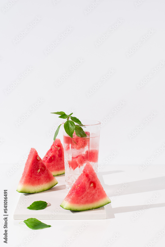 Vaso de zumo de sandía con trozos de sandia y hielo sobre fondo claro Vaso de zumo de sandía con trozos de sandia y hielo sobre fondo claro