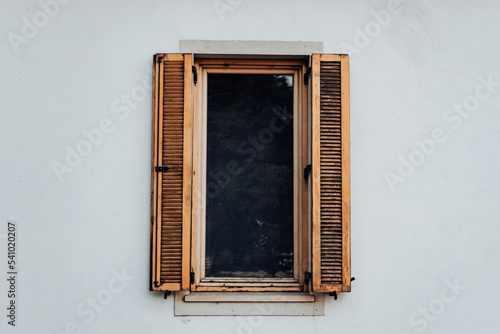 Vintage open window wood shutter on a white wall of a rustic home