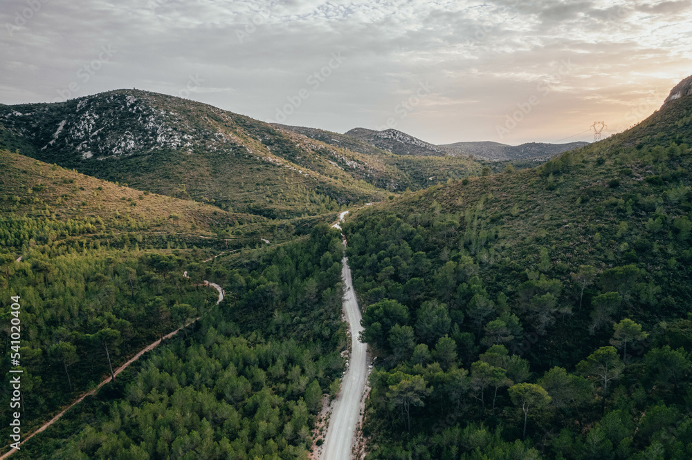 Fototapeta premium Drone view of savage road in the middle of the green forest and mountains