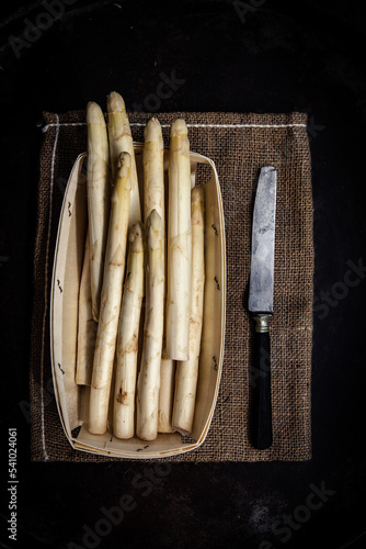 Asperges blanches dans une barquette en bois et un couteau, vu de dessus
