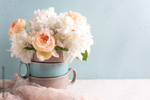 Romantic postcard with tender colorful summer roses and peonies flowers against blue background in vase. Selective focus. Place for text. Still life