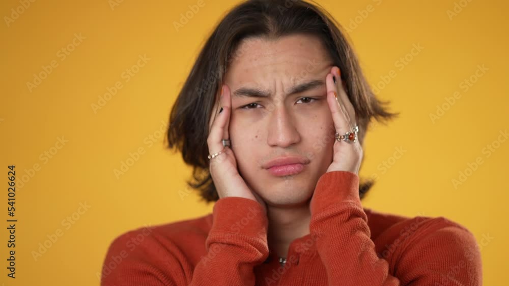 Sick tired headache exhausted displeased gender fluid young man 20s posing isolated on yellow background studio. People lifestyle concept. Put hands on head Sick tired headache exhausted displeased gender fluid young man 20s posing isolated on yellow background studio. People lifestyle concept. Put hands on head