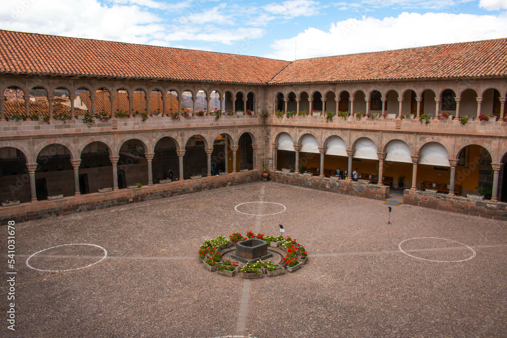 Inner courtyard with arches and columns, decorated with flowers, in Qorikancha, Church and Convent of Santo Domingo de Guzmán in Cusco. 