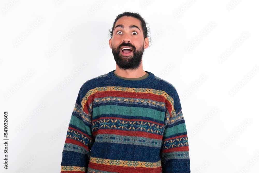 Shocked Caucasian man with beard wearing sweater over white background stares bugged eyes keeps mouth opened has surprised expression. Omg concept Shocked Caucasian man with beard wearing sweater over white background stares bugged eyes keeps mouth opened has surprised expression. Omg concept