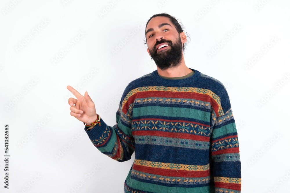 Naklejka premium Emotive Caucasian man with beard wearing sweater over white background keeps jaw dropped from shock demonstrates amazing promo points right on blank space demonstrates big shopping sale. Advertisement