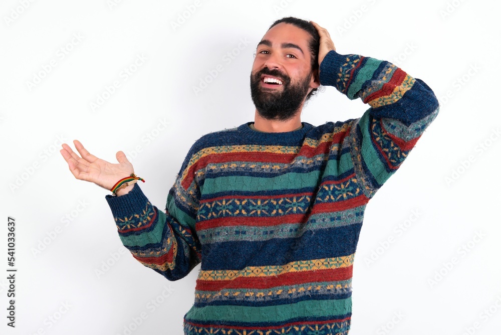 Fototapeta premium Shocked amazed surprised Caucasian man with beard wearing sweater over white background hold hand offering proposition