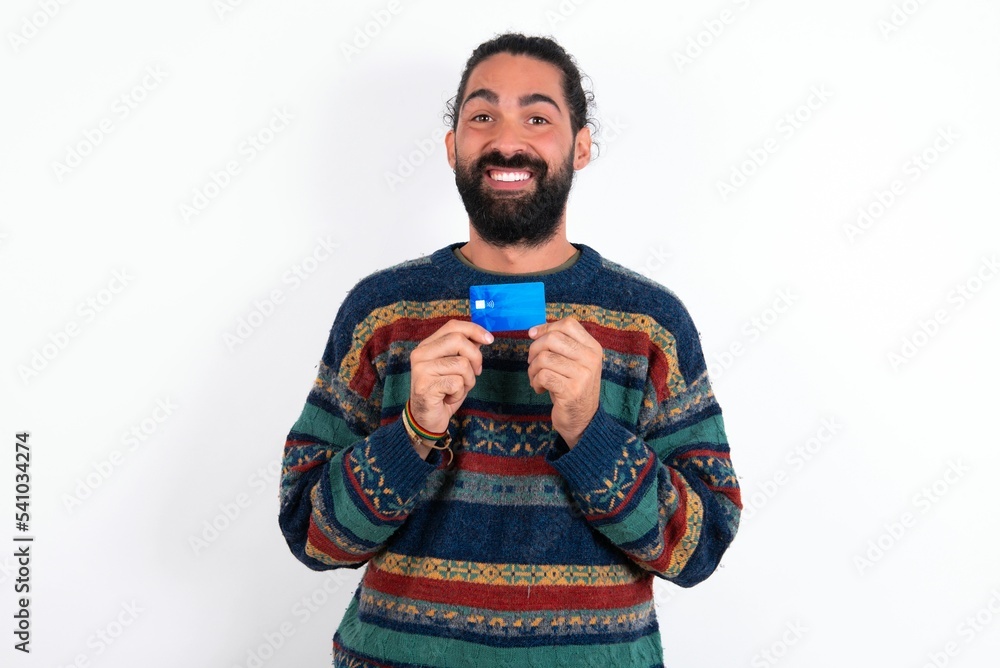 Photo of Caucasian man with beard wearing sweater over white background positive smile hold credit card income salary Photo of Caucasian man with beard wearing sweater over white background positive smile hold credit card income salary