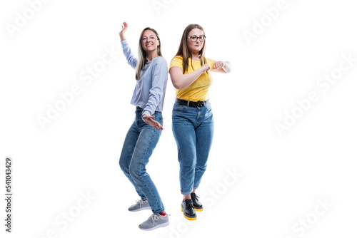 Two young girls are dancing. Girlfriends in jeans, blue and yellow T-shirts. Energy and activity. Full height. Isolated on white background.