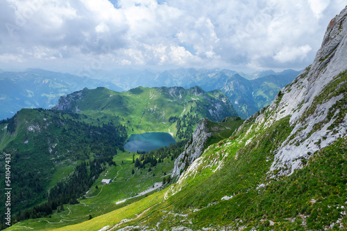 Panoramic view of lake, green alpine meadows and mountains