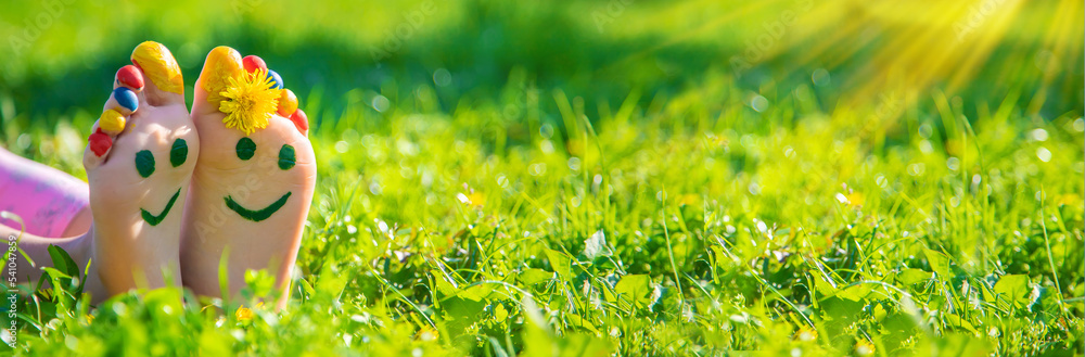 Fototapeta premium Child feet on the grass drawing a smile. Selective focus.