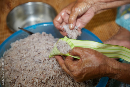 Hands of  senior woman wrapping the sticky rice with palm leaf or Ketupat Palas	 photo