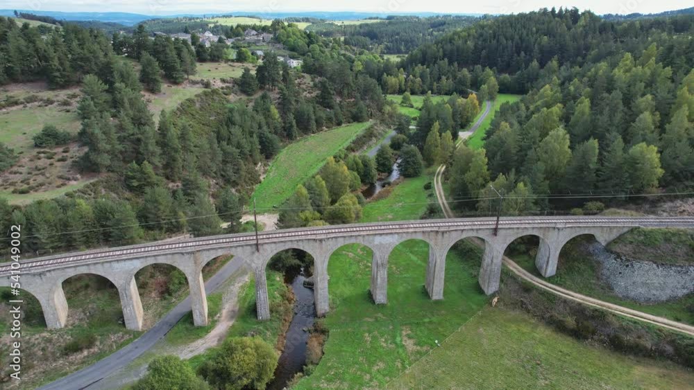 Old arched railway viaduct among the hills. Fairy-tale atmosphere, cows graze downstairs.