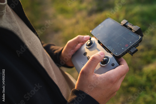 A man is operating a drone with a controller outside during the day