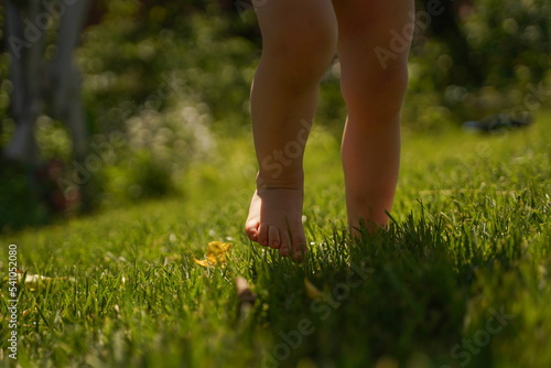 Boy feet in nature. bare feet in the green grass. little Happy child running at sunset barefoot outdoor. Happy childhood. Kid foot walking in green grass on garden. Barefoot concept and healthy feet