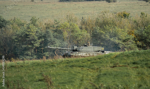 British army Challenger II 2 FV4034 main battle tank in action crossing open grass fields, on a military exercise Wiltshire UK