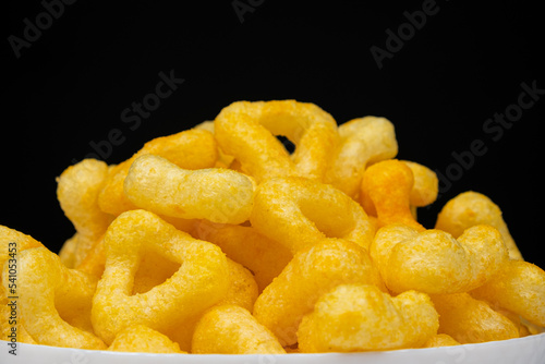 Delicious crispy corn chips with spices on a black background.