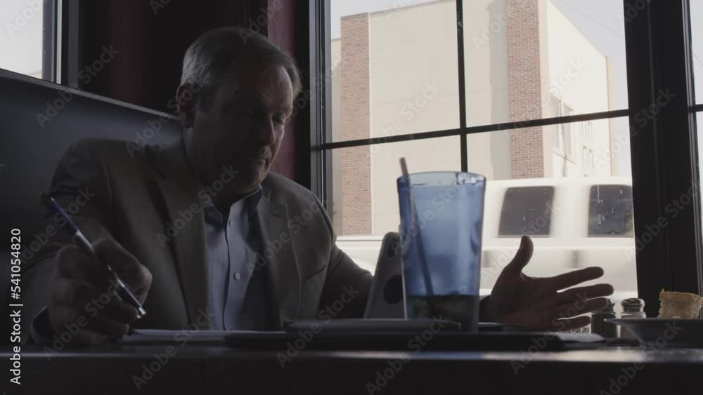 Close up low angle view of businessman video chatting in restaurant / Hermiston, Oregon, United States