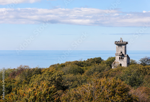 An old castle against the blue sky, the sea and the city. The tower on Mount Akhun in Sochi, Russia.