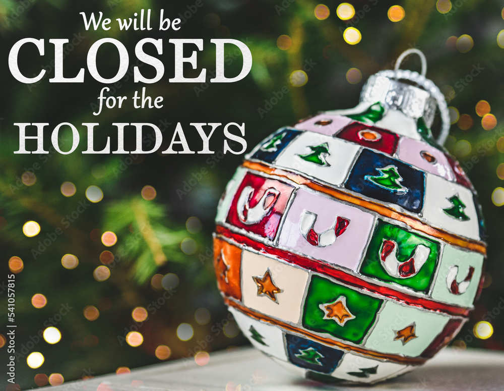 We will be closed for the Holidays. Beautiful signboard for Christmas and New Year holidays. Colorful Christmas balls on the background of the Christmas tree. Closeup, top view. Holidays concept
