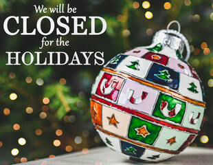 We will be closed for the Holidays. Beautiful signboard for Christmas and New Year holidays. Colorful Christmas balls on the background of the Christmas tree. Closeup, top view. Holidays concept
