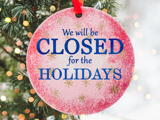 We will be closed for the Holidays. Beautiful signboard for Christmas and New Year holidays. Colorful Christmas balls on the background of the Christmas tree. Closeup, top view. Holidays concept