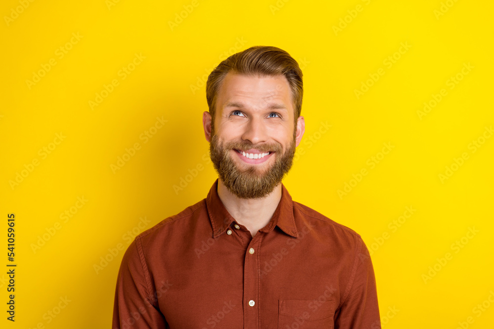 Fototapeta premium Photo of dreamy thoughtful positive man with blond beard dressed burgundy shirt look empty space isolated on yellow color background