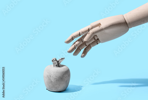 Wooden hand and stone apple on blue background photo