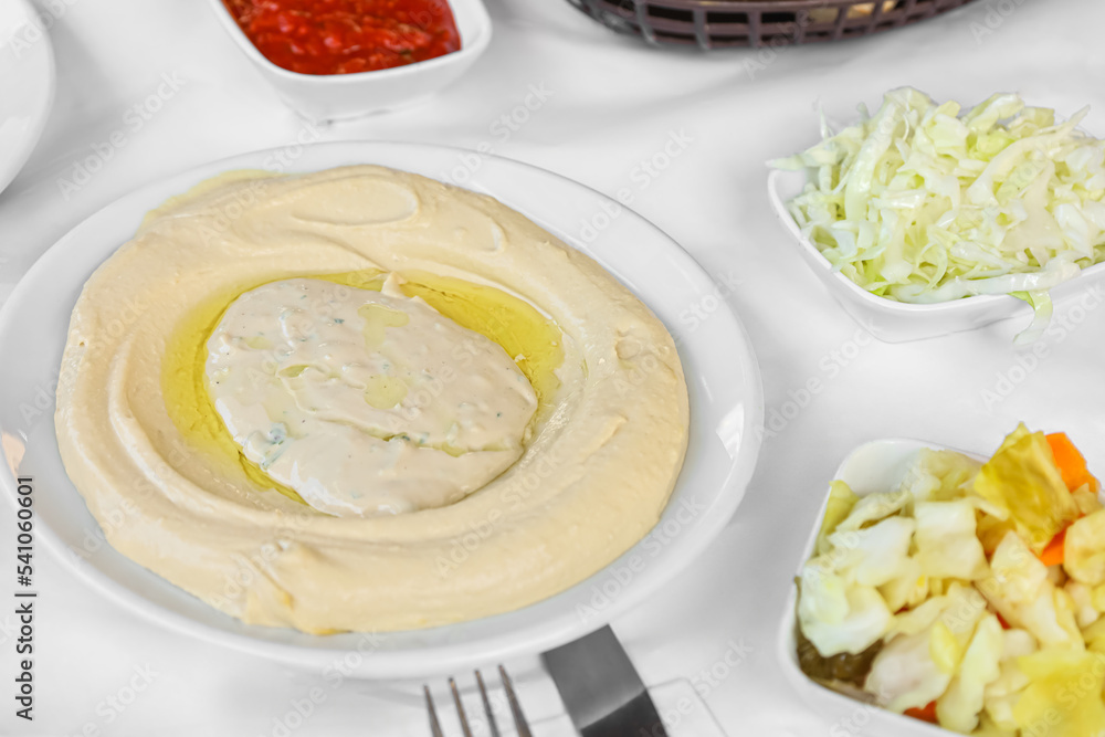 Plate with tasty hummus on table in restaurant, closeup Plate with tasty hummus on table in restaurant, closeup