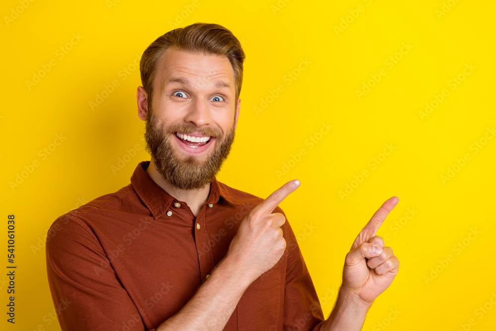 Photo of positive impressed cheerful man with blond beard wear burgundy shirt indicating empty space isolated on yellow color background