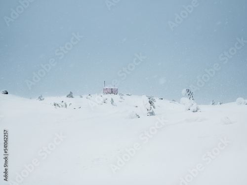 Soft focus. Poor visibility. Lonely house in a snowfall on a foggy snow-covered mountain. Winter holidays, extreme adventures in winter.