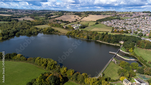 Aerial drone photo of the large Worsbrough reservoir in the village of Worsbrough, Barnsley in Sheffield in the UK, showing the British village and housing estates in the summer time