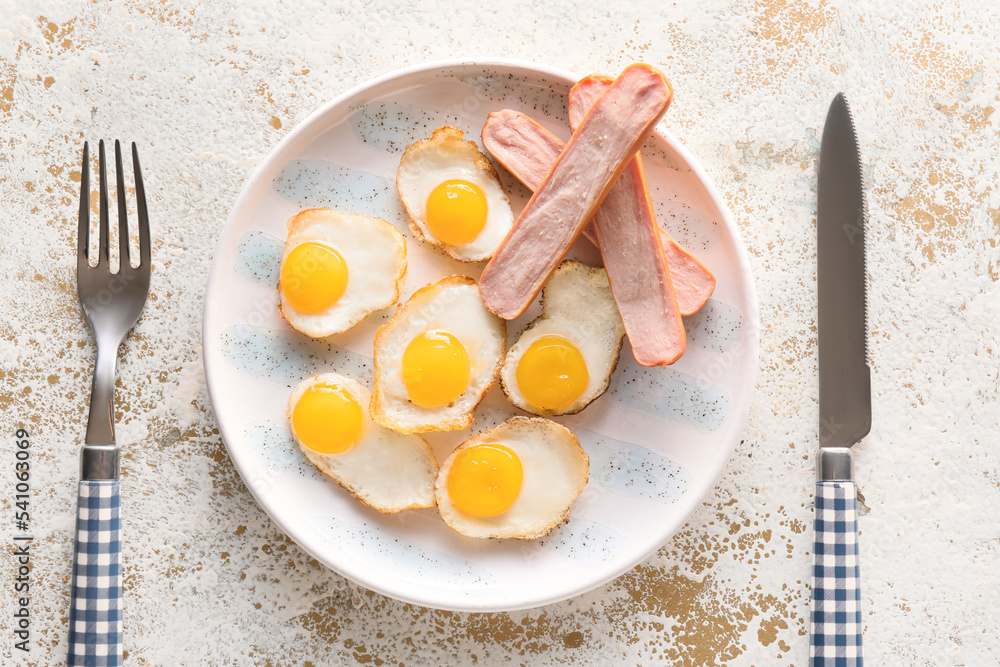Plate of tasty fried quail eggs with sausages on light background, closeup Plate of tasty fried quail eggs with sausages on light background, closeup