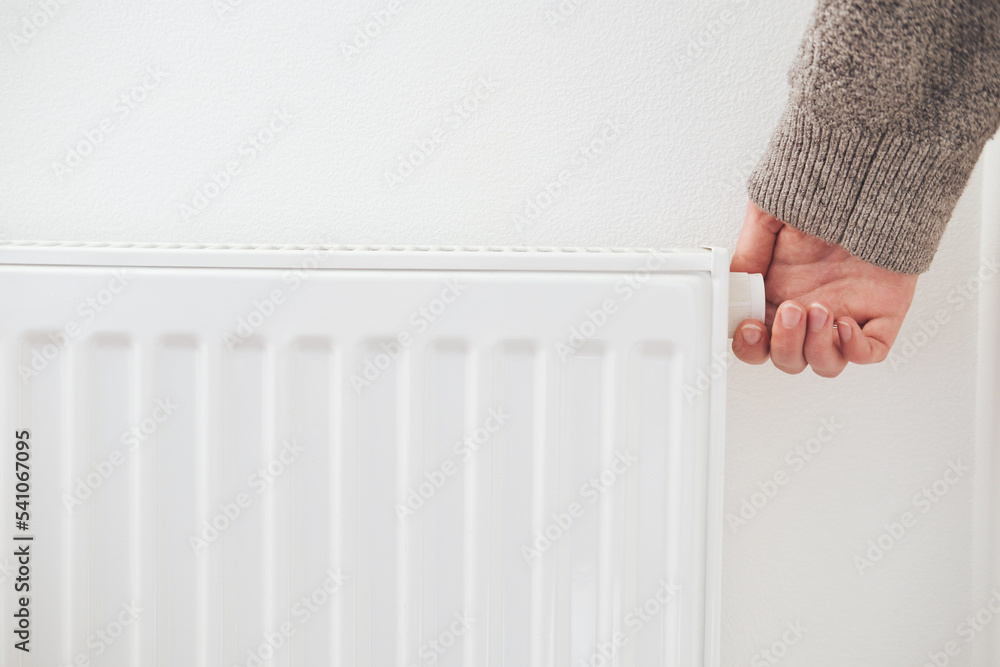 Hand turning down thermostat of a central heating radiator. Energy saving,  cold winter season, reduced power consumption and economy theme. Stock  Photo | Adobe Stock
