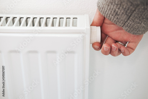 Turning down thermostat of a central heating radiator. Energy saving, cold winter season, reduced power consumption and economy theme.