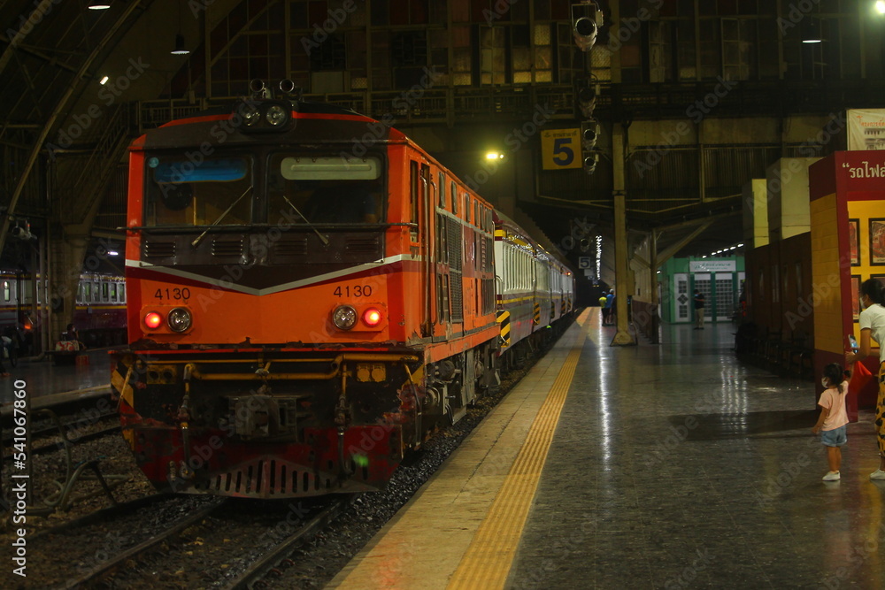 Inside Hua Lamphong Train Station with orange diesel locomotive in the night. Inside Hua Lamphong Train Station with orange diesel locomotive in the night.