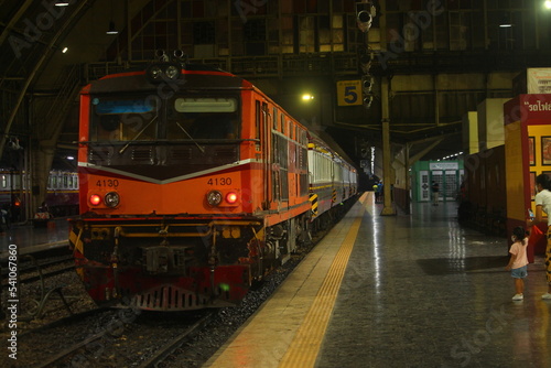Inside Hua Lamphong Train Station with orange diesel locomotive in the night.
