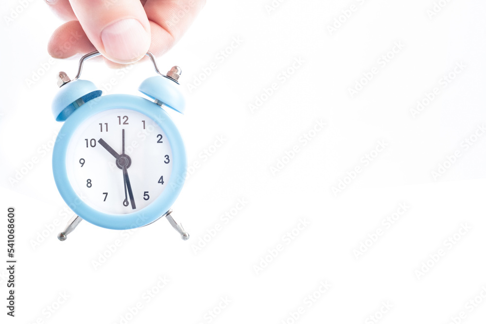 Small alarm clock in hand on a white background. Small alarm clock in hand on a white background.