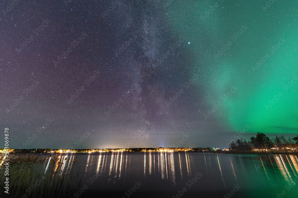 Beautiful Milky Way close to Aurora, scenic panorama of Northern Lights over calm night Stocksjo lake in Northern Sweden, Umea city. Night photo of starry sky.