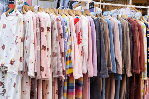 A shopping rank filled with clothes, pajamas and robes. Bunch of clothes of different colors for sale. Cheep clothing and fast fashion theme © boumenjapet
