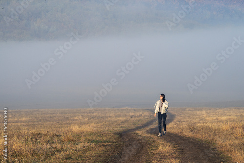 Misty  ground road filled with fog rural road countryside people girl  women walking Early morning landscape.  mist Autumn. minimalist Lonely sunrise Foggy Weather beautiful. © Victoria Moloman