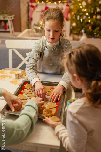 Girls have fun and joyfully prepare Christmas cookies at home in the kitchen