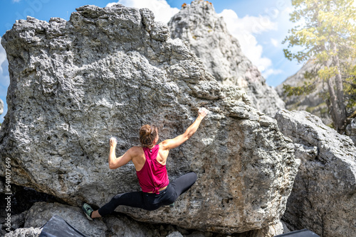 Sporty woman climbs on boulder block in the afternoon. Falzarego pass, Dolomites, South Tirol, Italy, Europe.