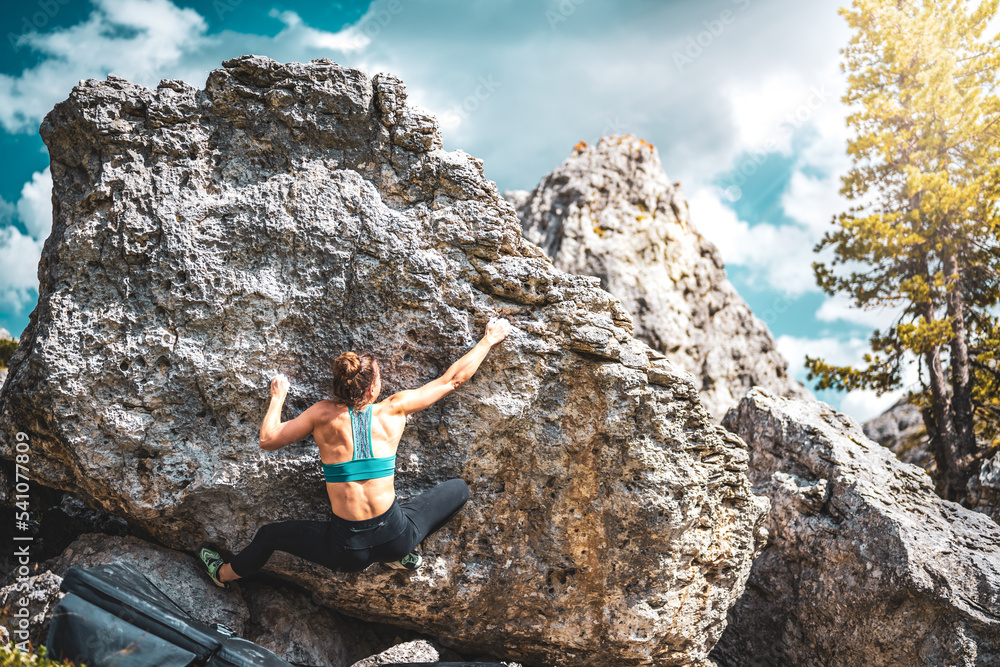 Sporty woman climbs on boulder block in the afternoon. Falzarego pass, Dolomites, South Tirol, Italy, Europe. Sporty woman climbs on boulder block in the afternoon. Falzarego pass, Dolomites, South Tirol, Italy, Europe.
